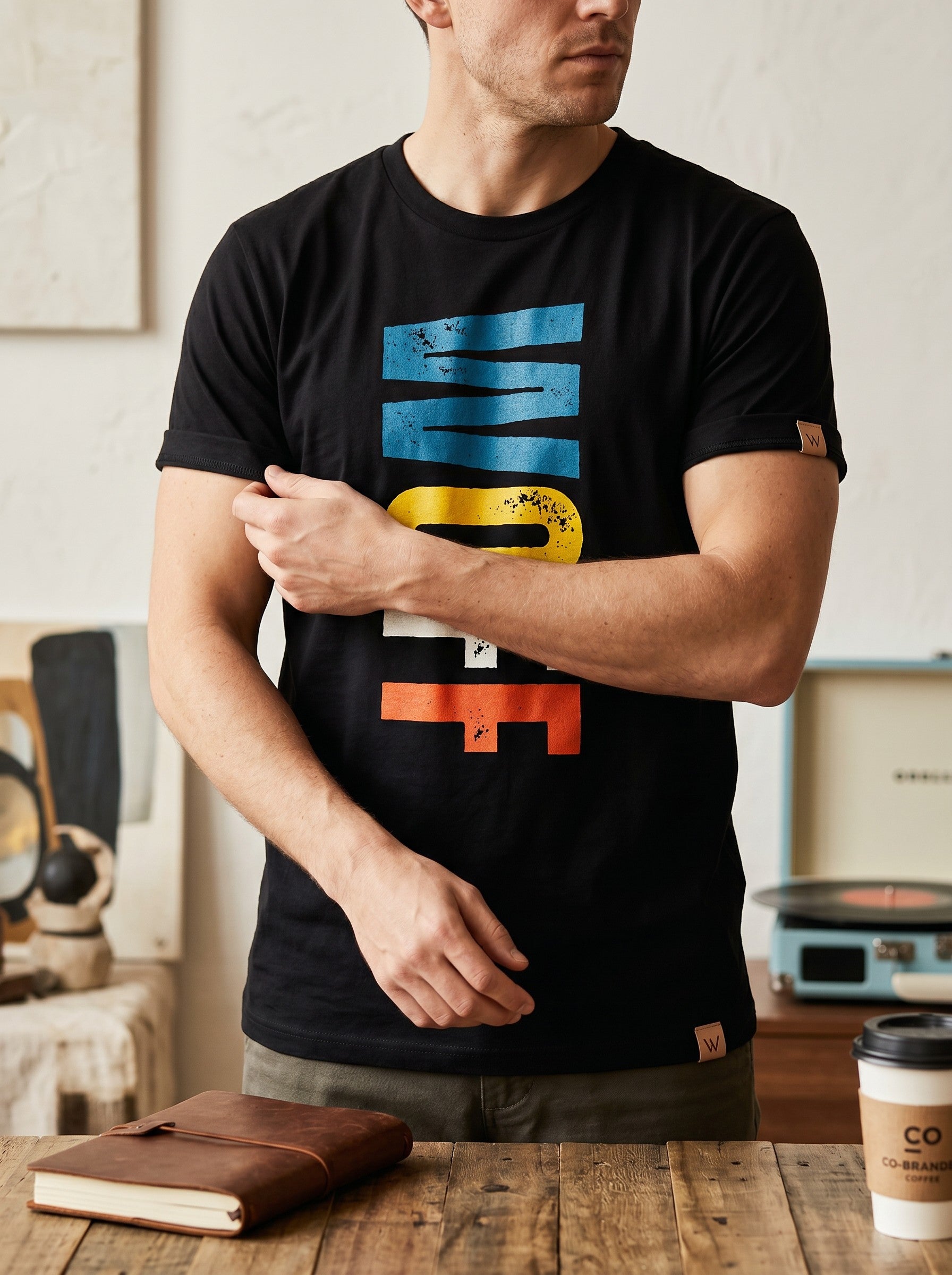 WOFF unisex black cotton t-shirt with a distressed blue, yellow, and orange graphic logo print on the chest.