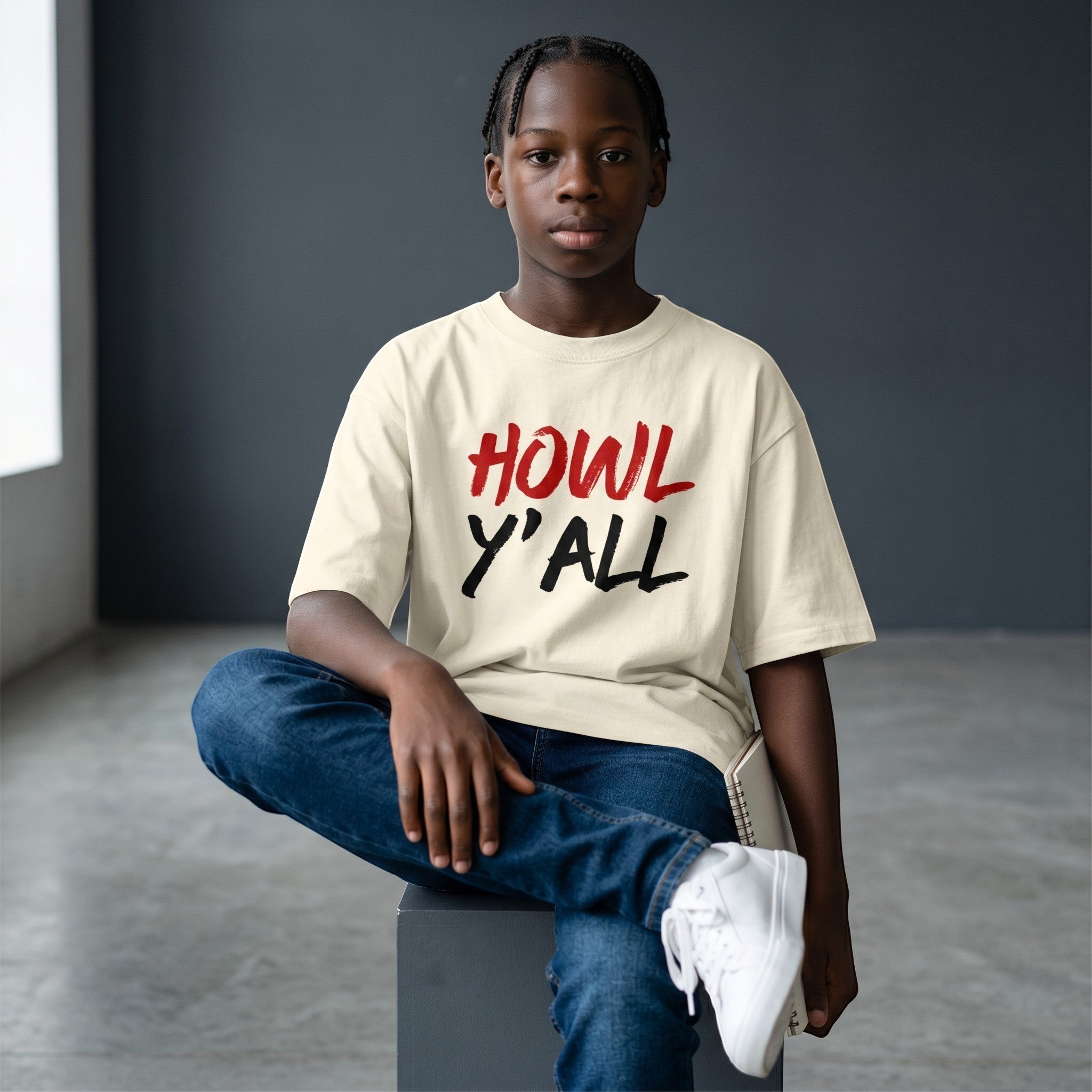 WOFF unisex oversized terry tee in cream with Howl Y'all graphic, worn by a young person sitting on a stool.