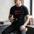 WOFF unisex black cotton crew neck t-shirt with red Lone Wolf graphic print worn by a man holding a coffee cup