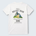 White 100% cotton crew neck t-shirt from WOFF featuring a graphic print of a wolf standing in front of mountains with the text "Where Wolves Roam" and "Strength Becomes Home".